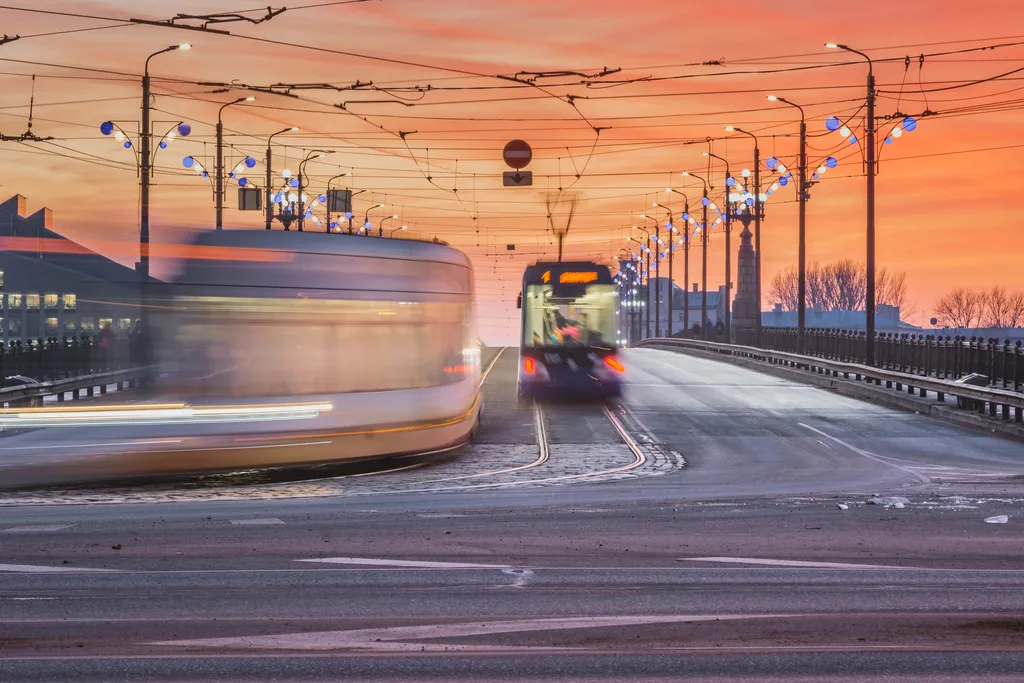 Sunset in Riga city with cars crossing the bridge creating light trails. Picturesque view on the highway with colourful sky.